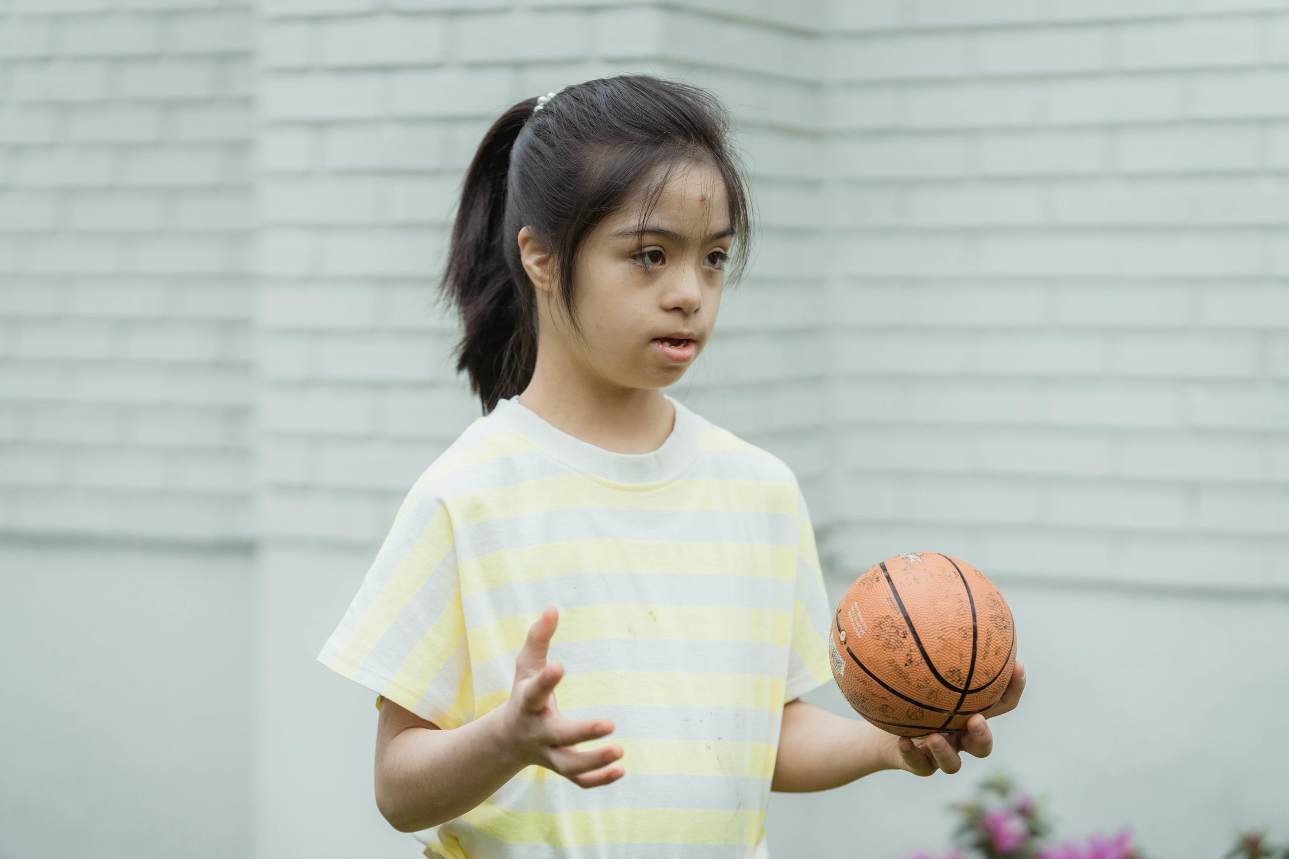 girl with autism holding a ball in one hand