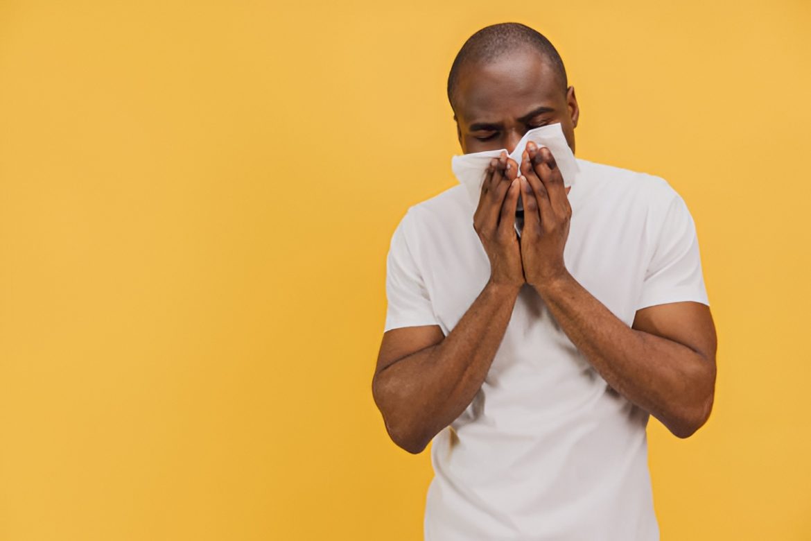 coughing man covering his nose and mouth with a tissue